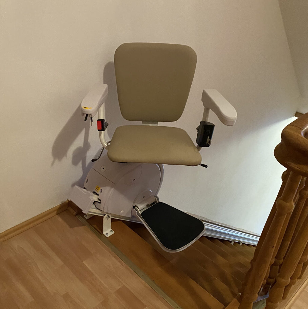 Stairlift in a home setting with wooden floor and staircase.