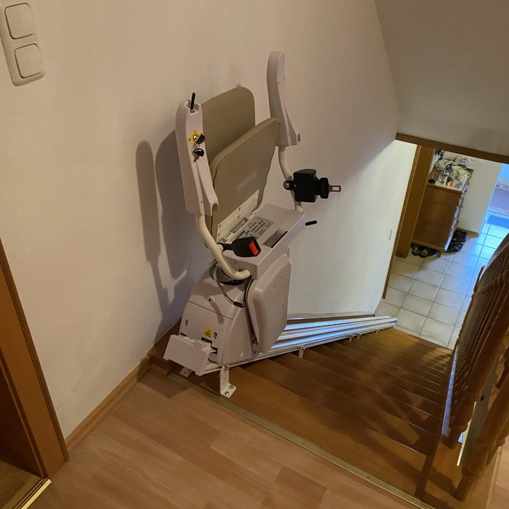 Stairlift installed on a set of wooden stairs inside a home.