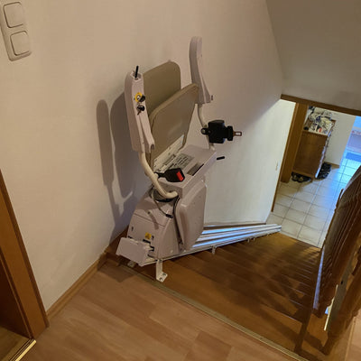 Stairlift installed on a set of wooden stairs inside a home.