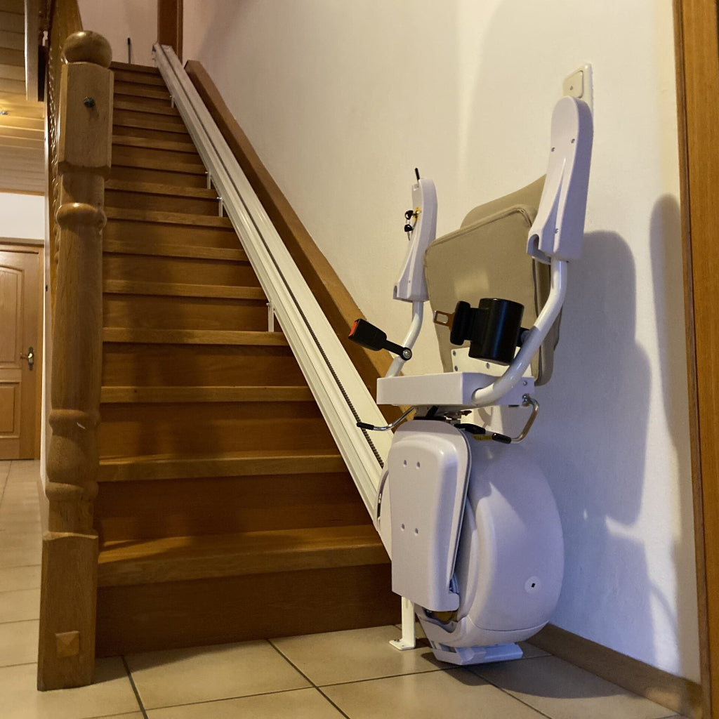 Stairlift attached to a wooden staircase in a home setting.