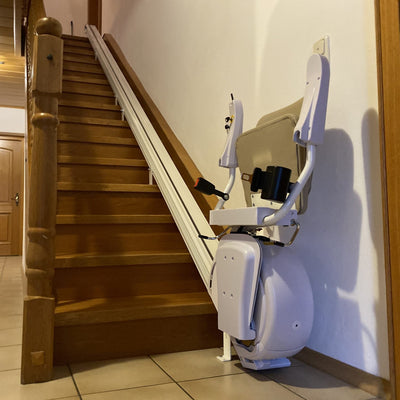 Stairlift attached to a wooden staircase in a home setting.