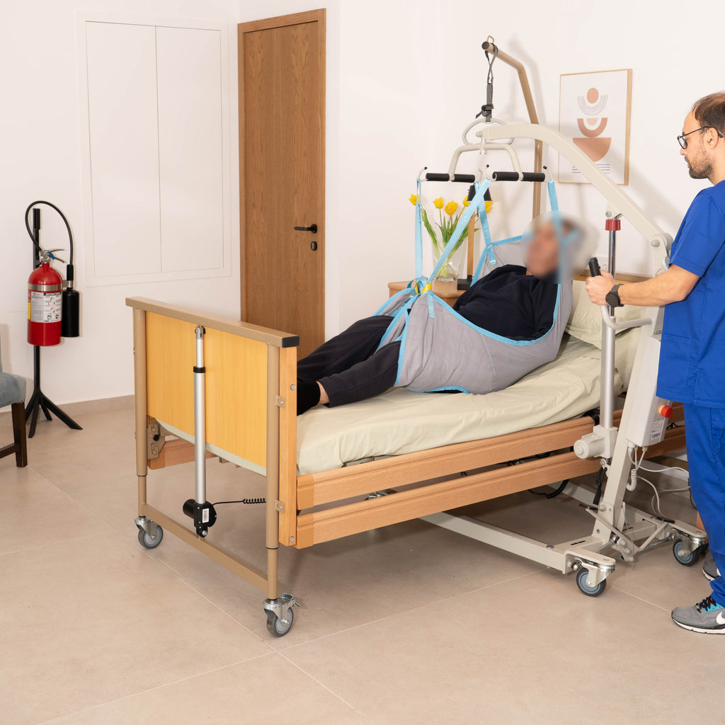 Mobiak Achilleas patient lift in use beside a care bed